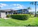 Beautiful backyard featuring green grass, manicured bushes, and screened-in patio with blue umbrellas at 9126 Shadowbrook Trl, Orlando, FL 32825