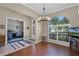 Dining room with wood floors, a modern chandelier, and a view into an office with large window at 9126 Shadowbrook Trl, Orlando, FL 32825