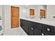 Bathroom features a long dark vanity with double sinks and a wood-paneled door at 10452 Log House Rd, Clermont, FL 34711