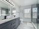 Well-lit bathroom featuring double sinks, granite countertops, stylish lighting, a walk-in shower, and neutral decor at 1225 Greenley Ave, Groveland, FL 34736