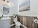 Charming powder room with a vanity, wainscoting, elegant mirror, and decorative artwork enhancing the cozy ambiance at 1225 Greenley Ave, Groveland, FL 34736
