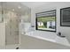 Bright bathroom features a soaking tub with a view of the backyard and a glass-enclosed shower at 1581 Forest Ave, Winter Park, FL 32789