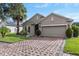 Inviting home with brick driveway and attached two-car garage framed by manicured landscaping and a shady tree at 528 Bridgeford Crossing Blvd, Davenport, FL 33837