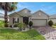 Attractive home with lush lawn, mature trees, brick driveway, and a welcoming front entrance at 528 Bridgeford Crossing Blvd, Davenport, FL 33837