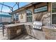 An outdoor kitchen featuring stone accents, a stainless steel grill, and a countertop bar at 528 Bridgeford Crossing Blvd, Davenport, FL 33837