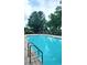 Relaxing community pool surrounded by lush greenery, lounge chairs, and a black fence for enhanced privacy at 528 Bridgeford Crossing Blvd, Davenport, FL 33837
