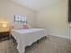 Simple bedroom featuring neutral carpet, window, side table and a queen bed with pillows at 554 Estates Pl, Longwood, FL 32779