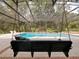 An outdoor pool with a bench swing, surrounded by tropical vegetation and screened enclosure at 554 Estates Pl, Longwood, FL 32779