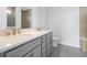 Elegant bathroom with dual sinks, gray cabinets and a tile shower at 10002 Brown Burrow St, Orlando, FL 32829