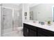 Modern bathroom with double sinks, black cabinets, a large mirror, and a glass enclosed shower with marble tile at 1013 Leader St, Davenport, FL 33896