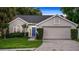 Charming single-story home with a well-manicured lawn, inviting blue door, and attached two car garage at 1027 Dees Dr, Oviedo, FL 32765