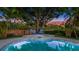 Inviting in-ground pool and spa with seating area, surrounded by lush landscaping and mature trees at sunset at 1027 Dees Dr, Oviedo, FL 32765