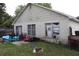 Exterior view of a single-story home with a backyard, showcasing faded siding, an above ground pool, and yard debris at 14057 Ithaca Way, Orlando, FL 32826