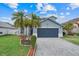 Charming blue two-story home featuring a two-car garage, landscaping, and palm trees at 1517 Abberton Dr, Orlando, FL 32837