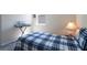 This well-lit bedroom features carpeted floors, a window with blinds, and a blue plaid comforter and lamp at 2340 Grasmere View S Pkwy, Kissimmee, FL 34746