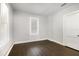Bright bedroom featuring sleek, dark wood floors and minimalist decor, illuminated by natural light from two windows at 2504 Yale Ave, Sanford, FL 32773