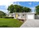 Charming single-story home featuring a well-manicured lawn, driveway, and gray painted exterior with a yellow door at 2707 Chelsea St, Orlando, FL 32803