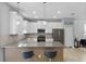 Stylish kitchen featuring white cabinets, stainless steel appliances, and breakfast bar with modern seating at 2934 Title St, Kissimmee, FL 34746