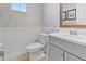 Tastefully decorated powder room featuring a white toilet, wainscoting, and a gray vanity at 2934 Title St, Kissimmee, FL 34746