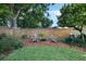 Wooded backyard with lounge furniture, mulched area, and privacy fence offers relaxation at 3015 Dawley Ave, Orlando, FL 32806