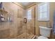 Bathroom with tiled shower, clear glass door, tan walls, white trim and toilet, and a shuttered window at 3015 Dawley Ave, Orlando, FL 32806