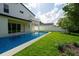 Backyard view featuring a modern pool with blue tile, lush green lawn and a stylish two-story home at 3608 Dubsdread Cir, Orlando, FL 32804