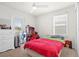 Cozy bedroom featuring a vibrant red bedspread, a ceiling fan and plenty of natural light at 5826 Wooden Pine Dr, Orlando, FL 32829