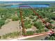 Aerial view of a spacious property outlined in red, near a lake and surrounded by dense trees at 6037 Lake Erie Rd, Groveland, FL 34736