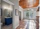 Foyer and hallway featuring hardwood floors and a wood-paneled ceiling, leading to a powder room at 6037 Lake Erie Rd, Groveland, FL 34736