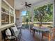 Relaxing screened-in porch with wood floors, ceiling fan, comfortable seating, and scenic backyard views at 6037 Lake Erie Rd, Groveland, FL 34736