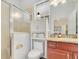 Updated bathroom with walk-in shower, storage cabinet, granite countertop, and decorative lighting at 6816 Greengrove Blvd, Clermont, FL 34714