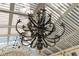 Close-up of a grand, ornate chandelier with leaf detailing hanging from a white-striped ceiling at 6816 Greengrove Blvd, Clermont, FL 34714