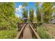 Charming wooden deck overlooking a tranquil water feature, surrounded by lush greenery and mature bamboo trees at 6816 Greengrove Blvd, Clermont, FL 34714