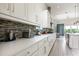 White kitchen showcasing a gray backsplash, ample counter space, and stainless steel appliances at 7928 Jacks Club Dr, Kissimmee, FL 34747