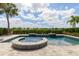 Beautiful pool and spa area with palm trees, black fence, and lush hedges create a private backyard oasis at 7928 Jacks Club Dr, Kissimmee, FL 34747