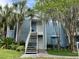 A charming blue two-story condo with a white staircase, surrounded by lush landscaping and mature trees at 2524 Grassy Point Dr # 104, Lake Mary, FL 32746