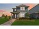 Charming two-story home featuring a quaint front porch and well-manicured lawn under a captivating sunset sky at 10209 Folly Beach Rd, Orlando, FL 32827