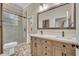 Bathroom featuring double sinks, light wood cabinets, and glass-enclosed shower with neutral tile at 1130 Roxboro Rd, Longwood, FL 32750