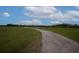 View of a dirt driveway leading through a large green field at 11320 Montevista Rd, Clermont, FL 34711