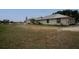 Exterior view of the backyard and side of a tan single story home with metal roof at 11320 Montevista Rd, Clermont, FL 34711