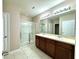 This primary bathroom features dual sinks, dark wood cabinets, and a glass-enclosed shower at 133 Grove Branch Rd, Winter Haven, FL 33880