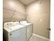 Well-lit laundry room with white appliances and overhead wire shelving for storage at 133 Grove Branch Rd, Winter Haven, FL 33880
