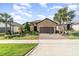 Charming single-story home with a well-manicured lawn, paver driveway, and lush tropical landscaping at 1335 Zeek Ridge St, Clermont, FL 34715
