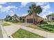 Attractive home exterior featuring palm trees, lush greenery, a paved driveway, and neatly trimmed lawn at 1335 Zeek Ridge St, Clermont, FL 34715
