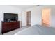 Spacious bedroom featuring tile flooring, a large dresser with TV, and an ensuite bathroom at 16369 Yelloweyed Dr, Clermont, FL 34714