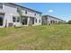 View of a large grassy backyard with a row of townhouses, sliding glass doors, and small patios at 16403 Bird Of Paradise Ave, Clermont, FL 34714