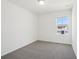 Bright, simple bedroom with neutral carpet, white walls, and a view of a nearby home at 16403 Bird Of Paradise Ave, Clermont, FL 34714