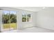 Bright, open living room featuring large windows, sliding glass doors, and light tile flooring at 16403 Bird Of Paradise Ave, Clermont, FL 34714