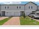 Charming townhome exterior with gray siding, brick driveway, and well-maintained landscaping at 16443 Bird Of Paradise Ave, Clermont, FL 34714