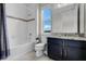 Bright bathroom featuring tiled shower-tub, dark vanity and a large window for natural light at 1910 Donahue Dr, Ocoee, FL 34761